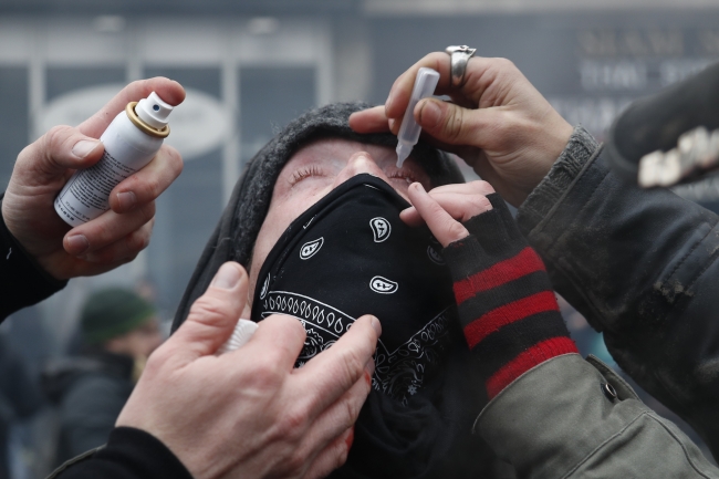 Polisin kullandığı gazlara karşı koruyucu göz damlası kullanan bir gösterici. 5 Aralık 2019, Paris | Fotoğraf: AFP